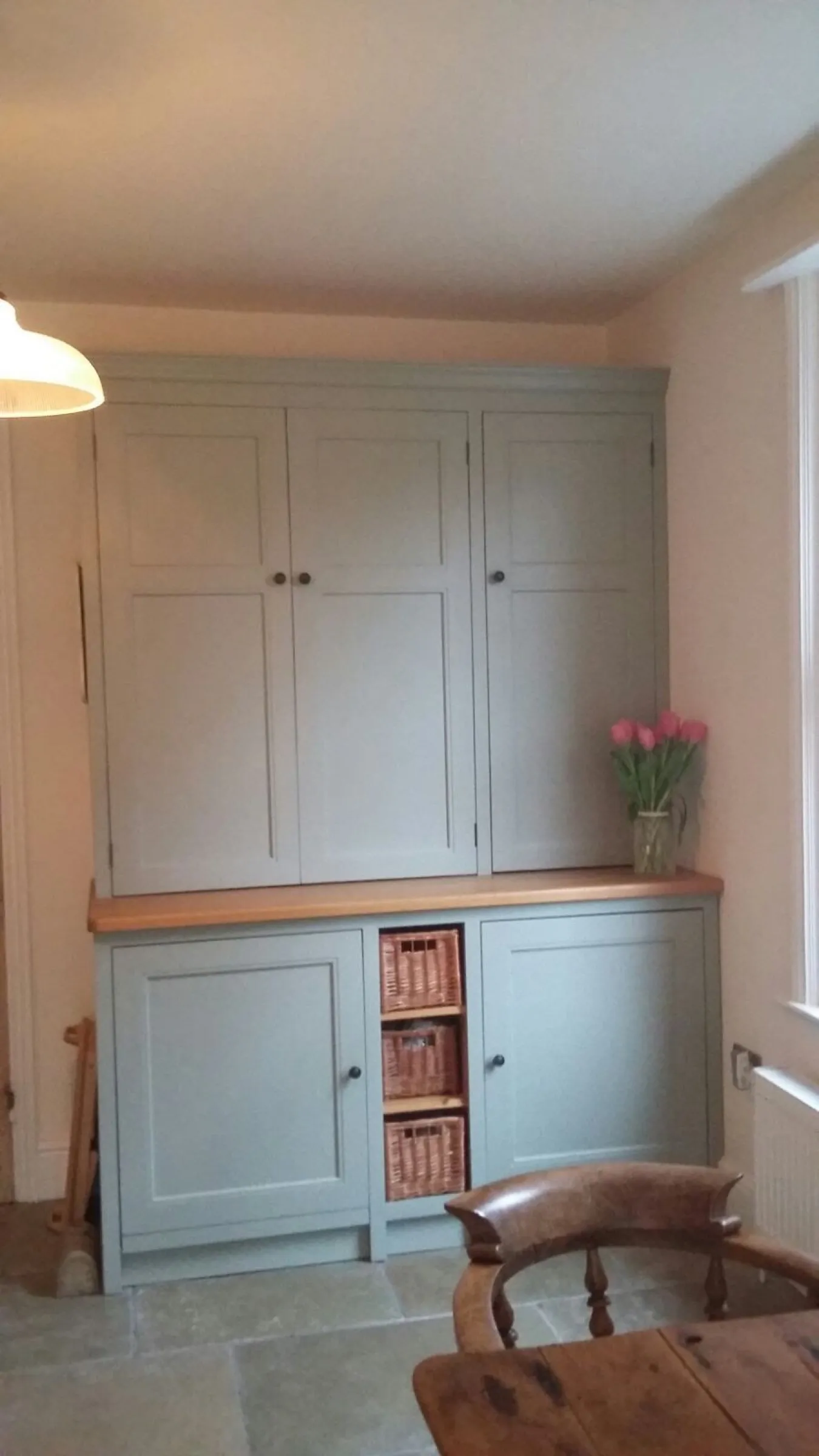 Floor-to-ceiling painted larder dresser with an oak counter and wicker storage baskets