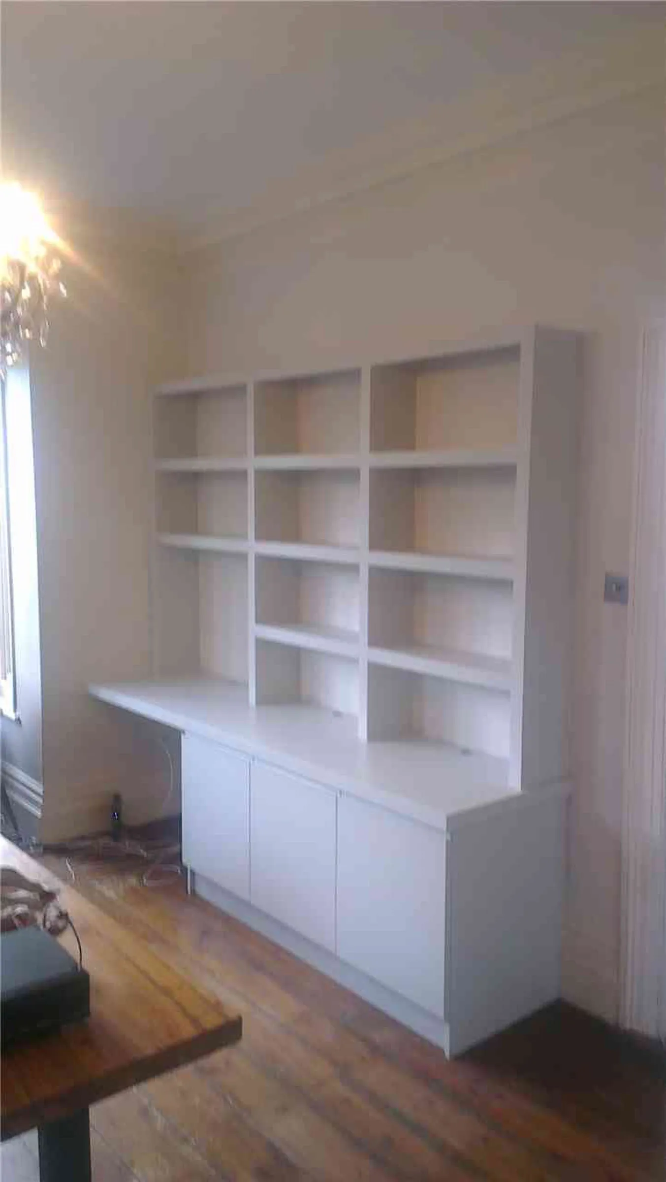 Tall painted bookcase with cupboard base and adjoining floating desk top in a period living room