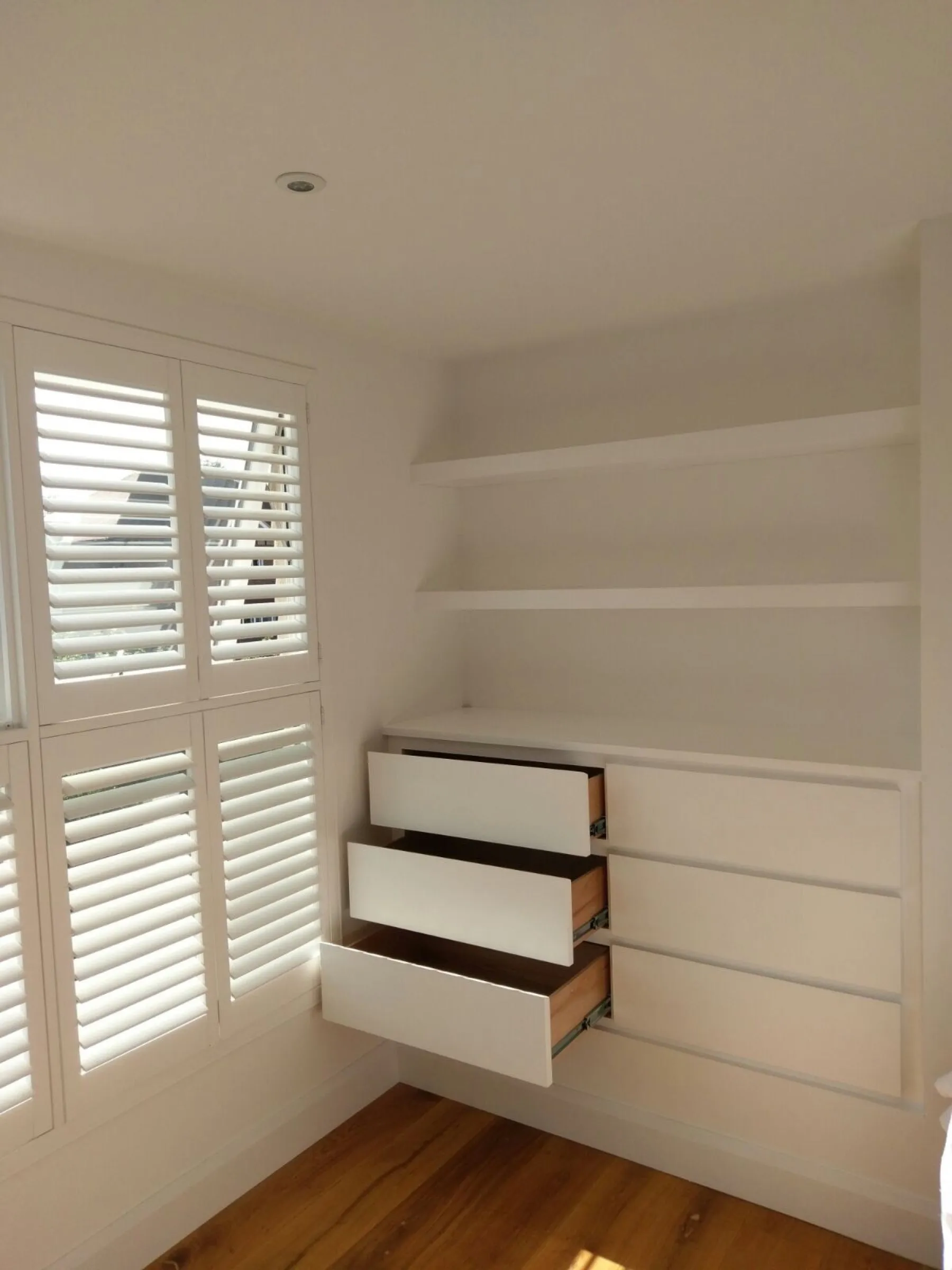 Overhead detail of open plywood drawer boxes on metal runners in a fitted loft bedroom unit