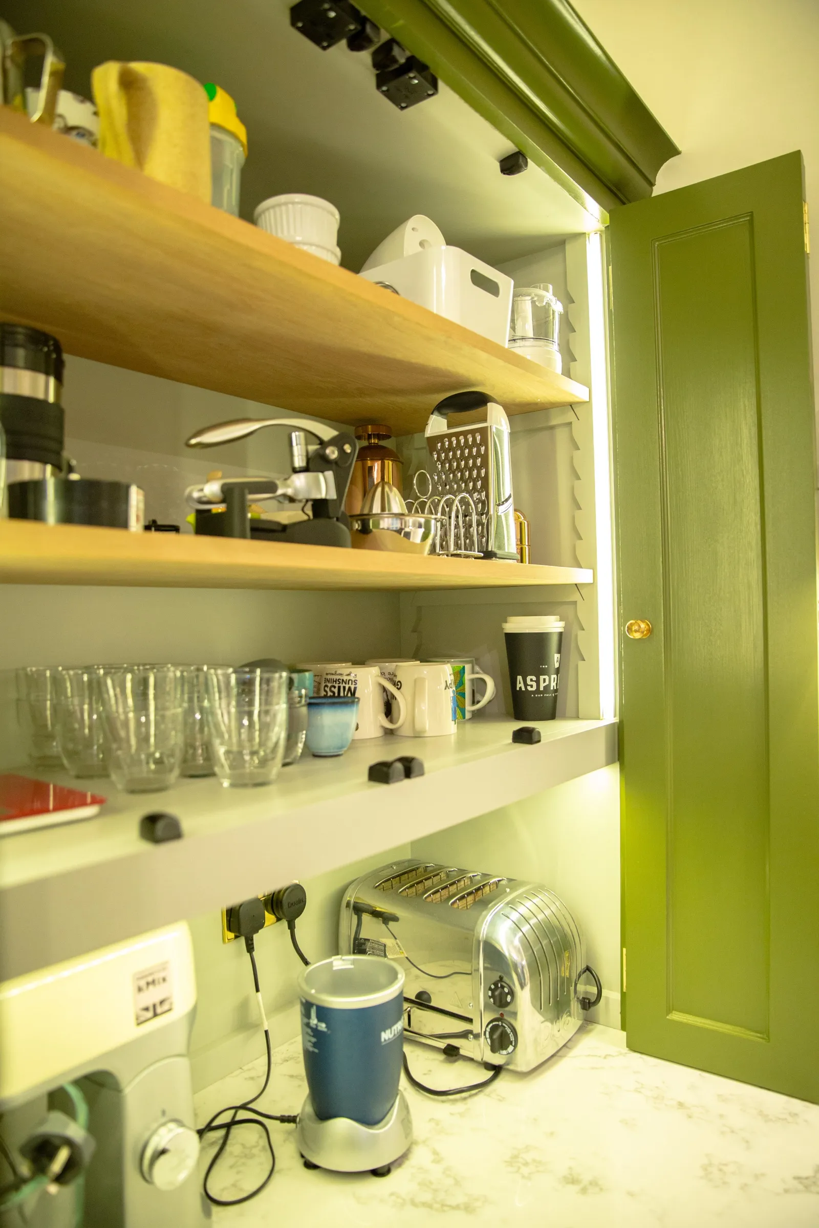 Inside the appliance pantry, with oak shelving, integrated sockets and lighting, and the toaster, mixer and blender on the worktop