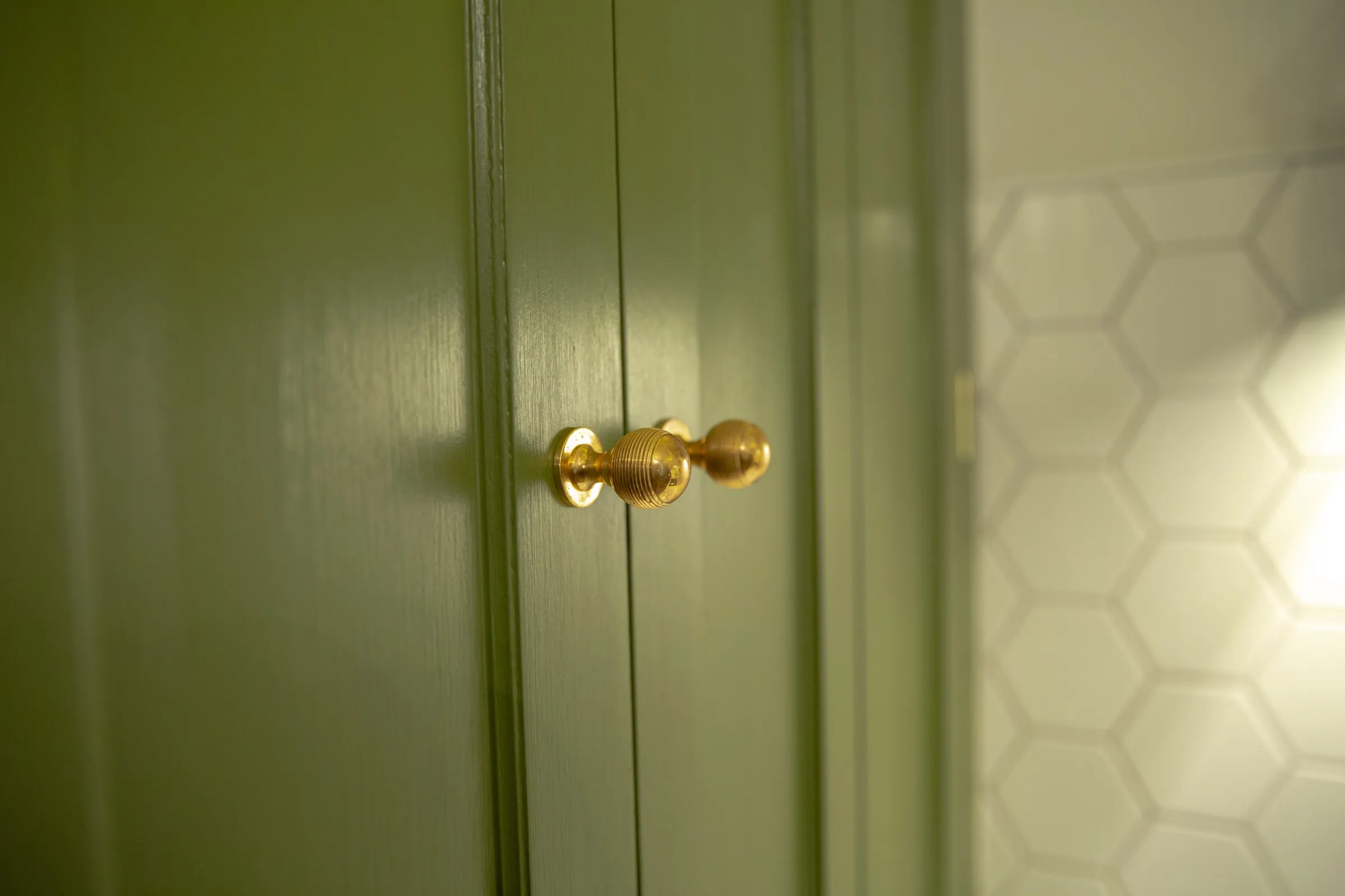 Pair of brass beehive knobs on the hand-painted green cupboard doors