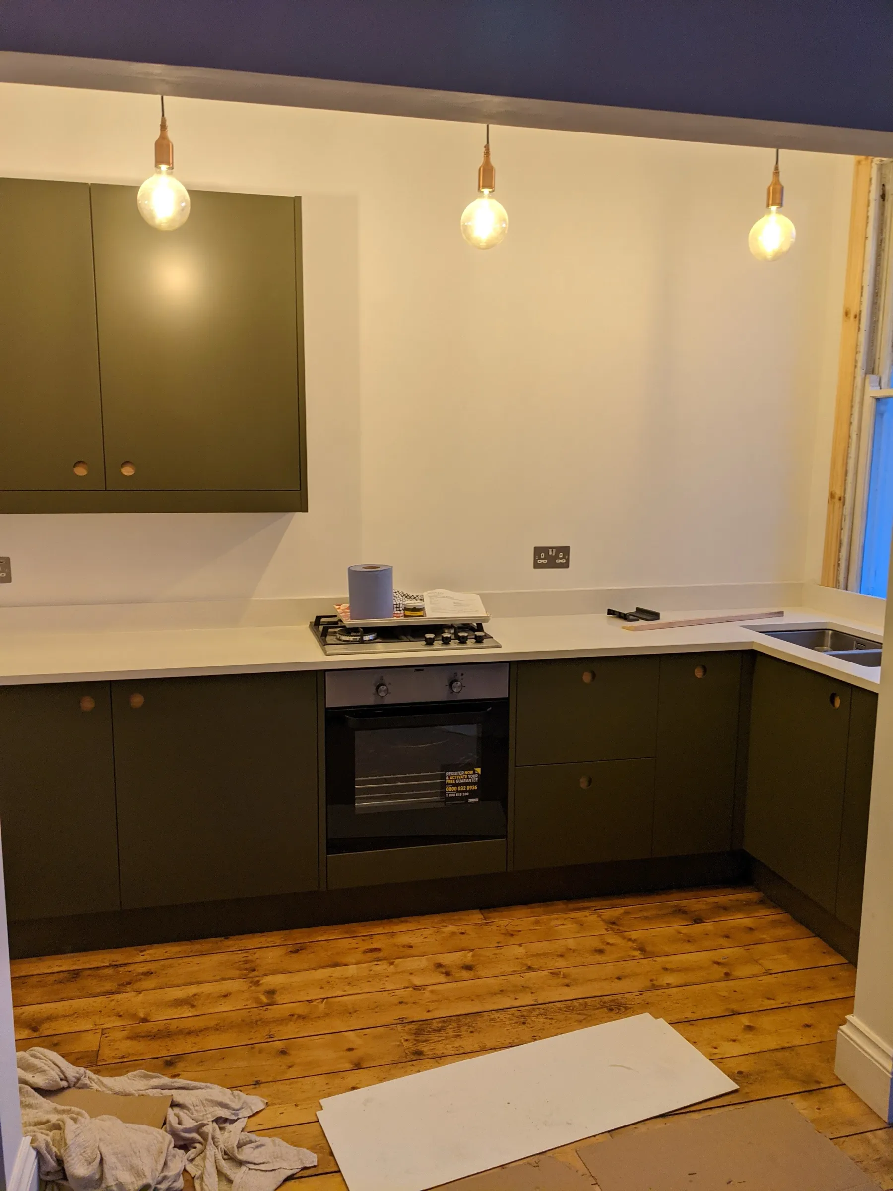 Graphite gloss galley kitchen with concrete-effect worktop, chunky oak shelves and stainless steel chimney hood