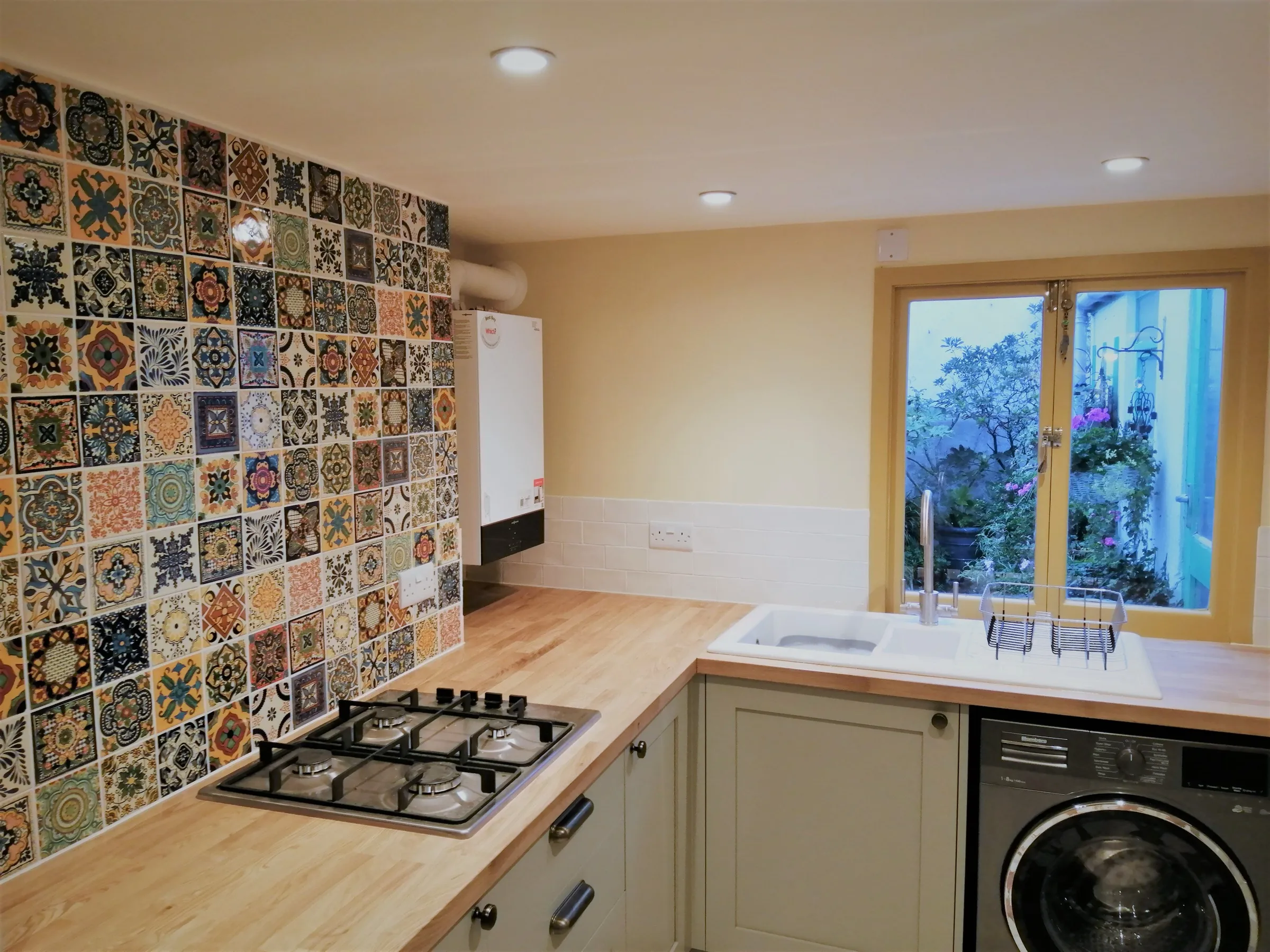 Sage green Shaker kitchen with Mexican tile feature wall, oak worktops and integrated washing machine