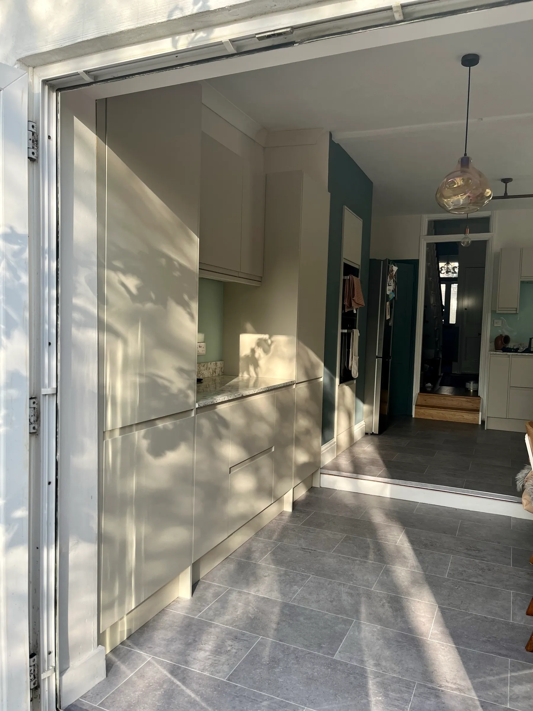 Cashmere handleless tall units and granite worktop seen from the open garden doors