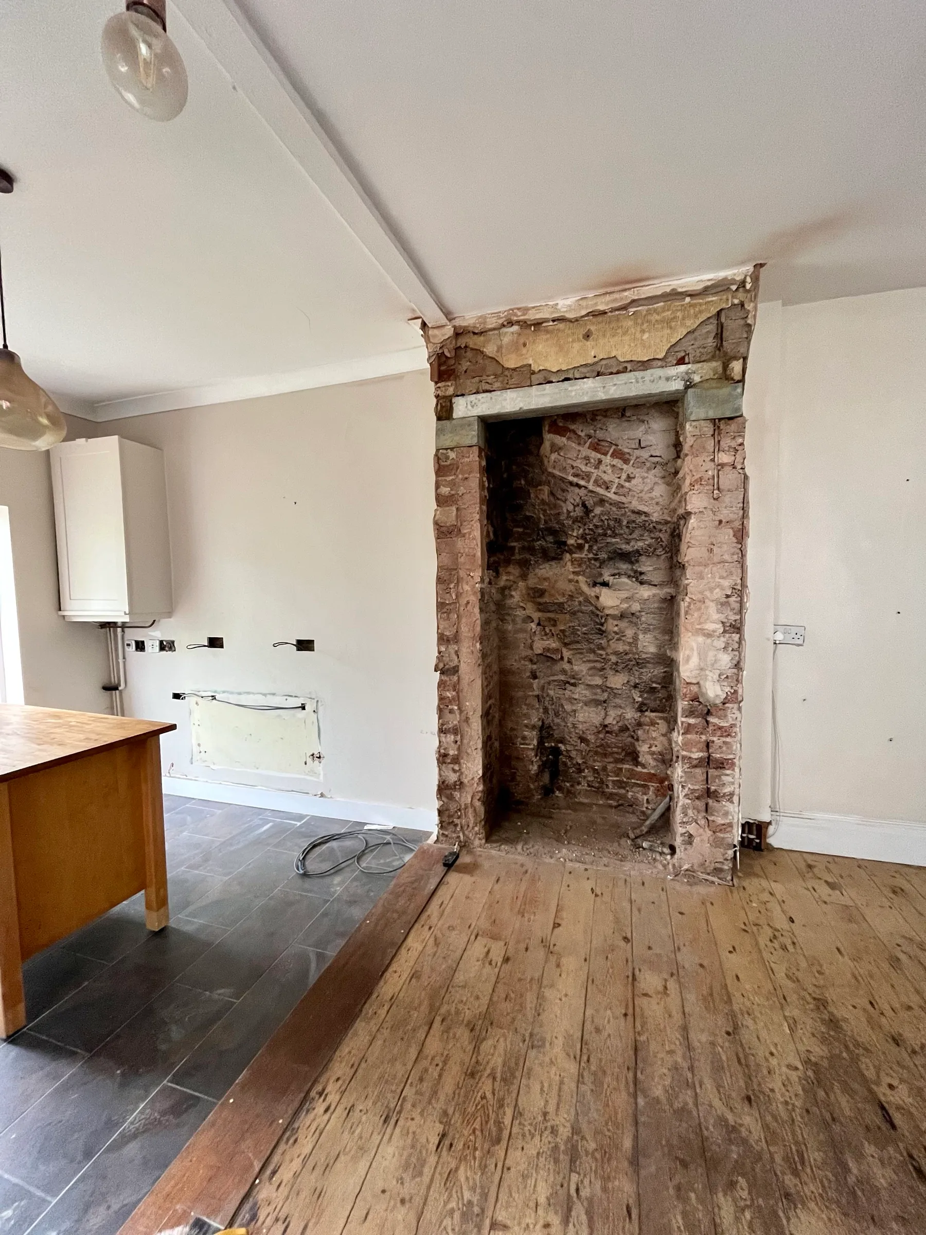Strip-out stage of a kitchen renovation with the chimney breast opened up to exposed brick