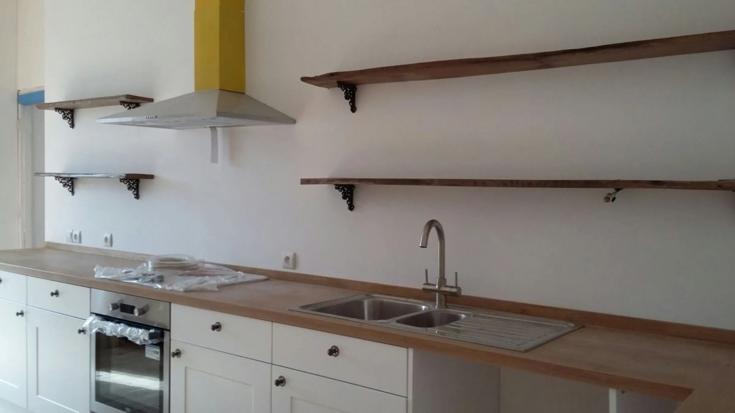 Cream Shaker kitchen with double-bowl stainless sink, swan-neck tap and oak worktops, appliances still in protective wrapping