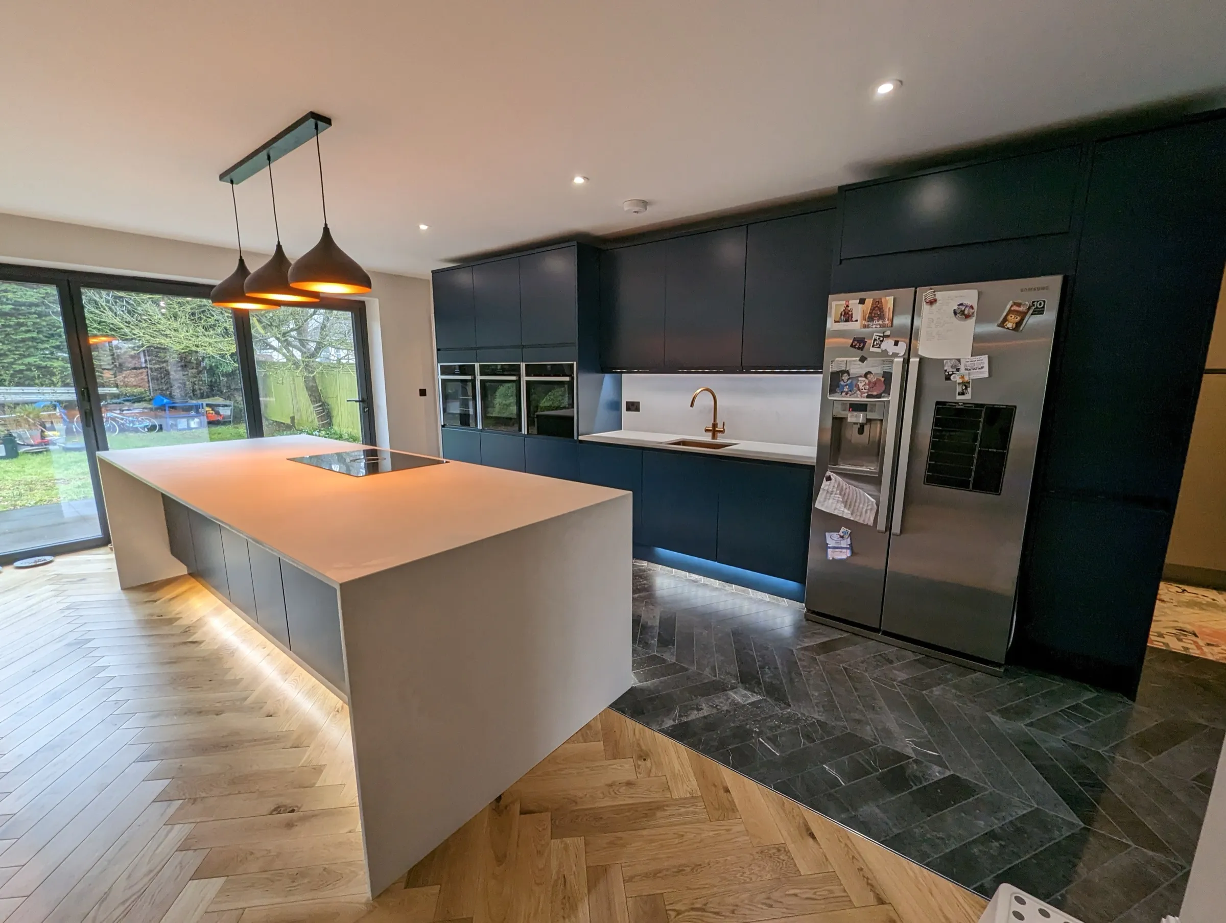 Sage green Shaker kitchen with oak worktops, white metro tiles and black chimney hood
