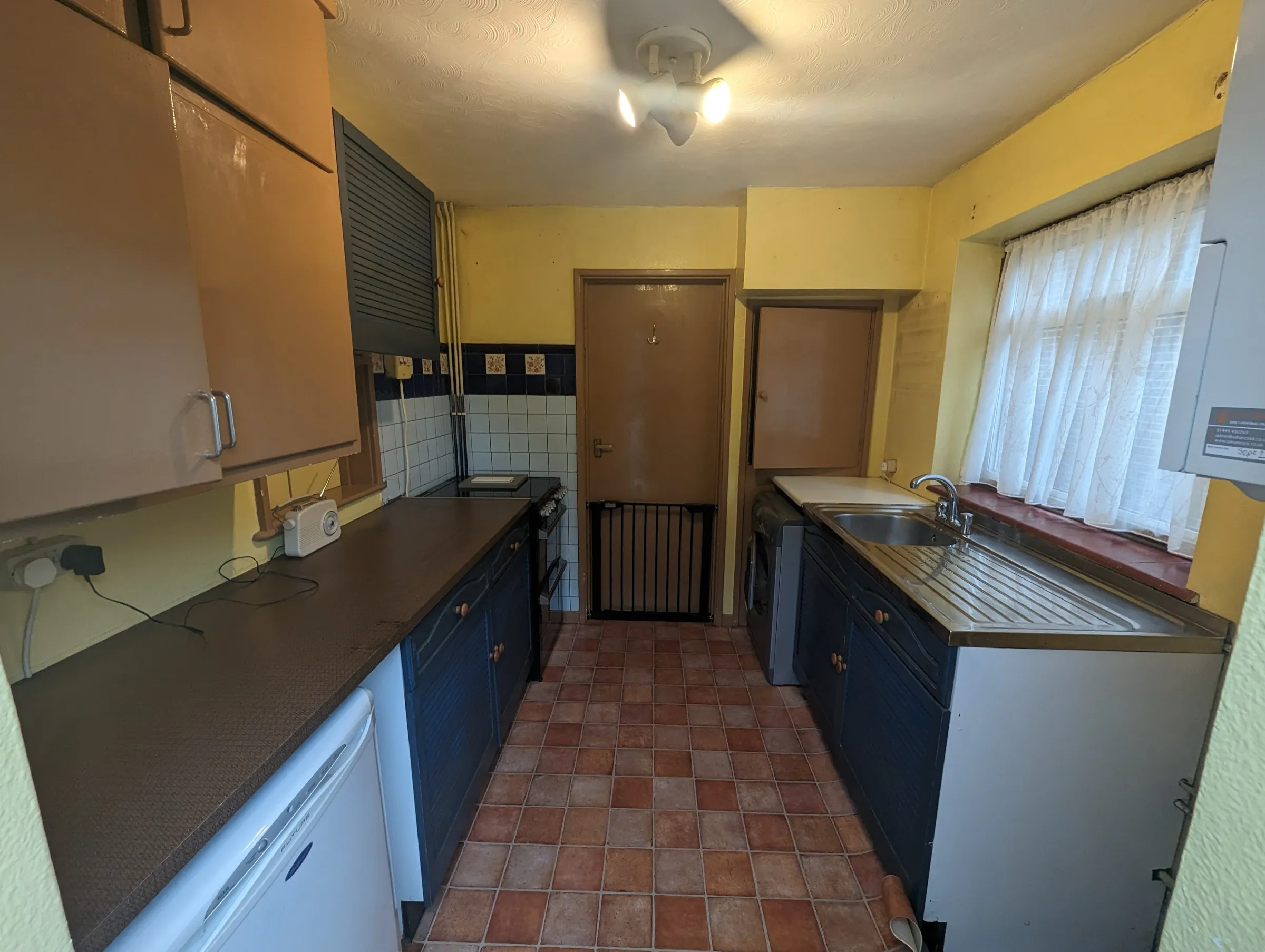 Before the refit: the dated galley kitchen with louvre-front units and terracotta-style floor tiles