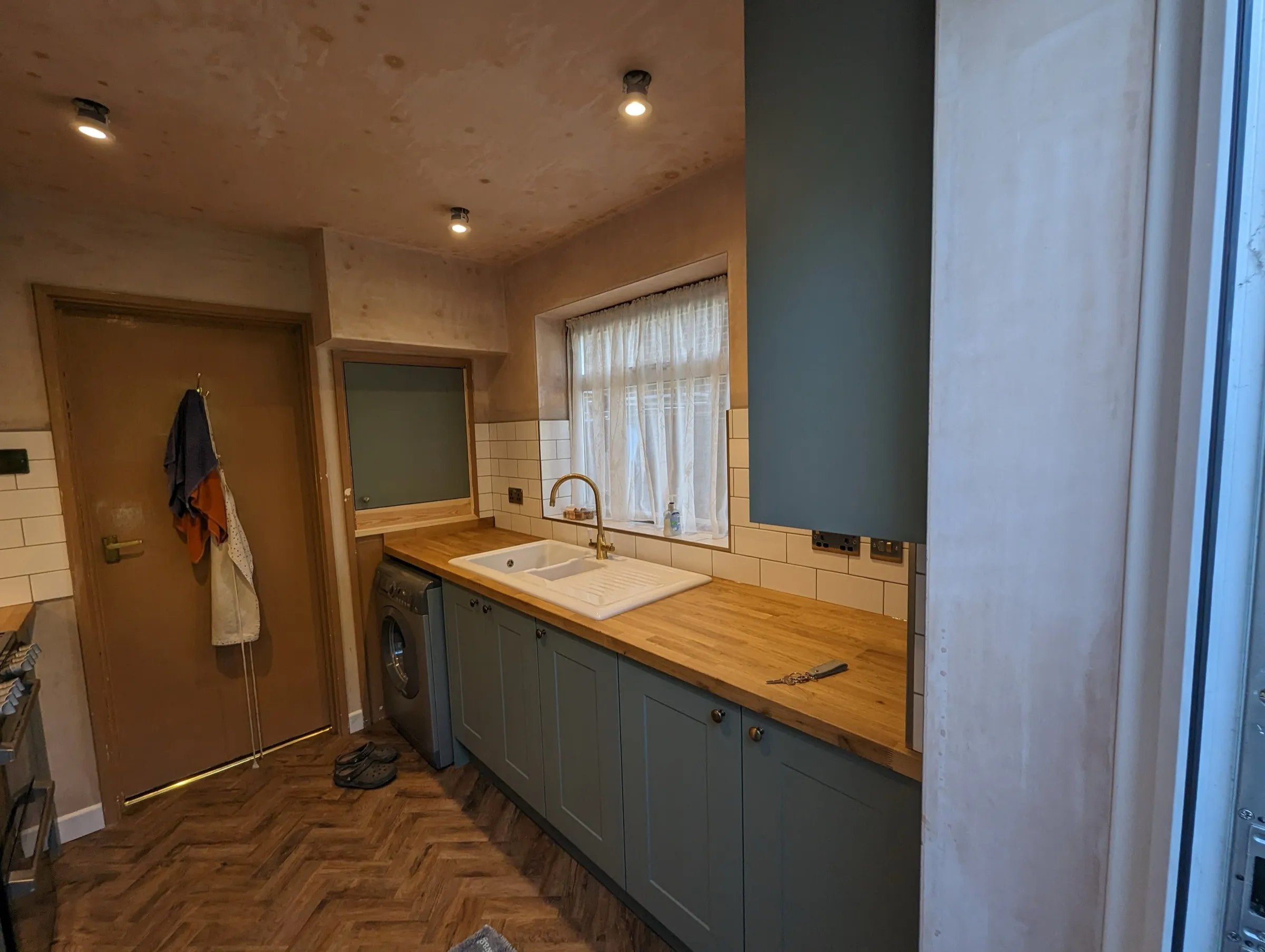 Ceramic double sink and antique brass mixer tap beneath the window