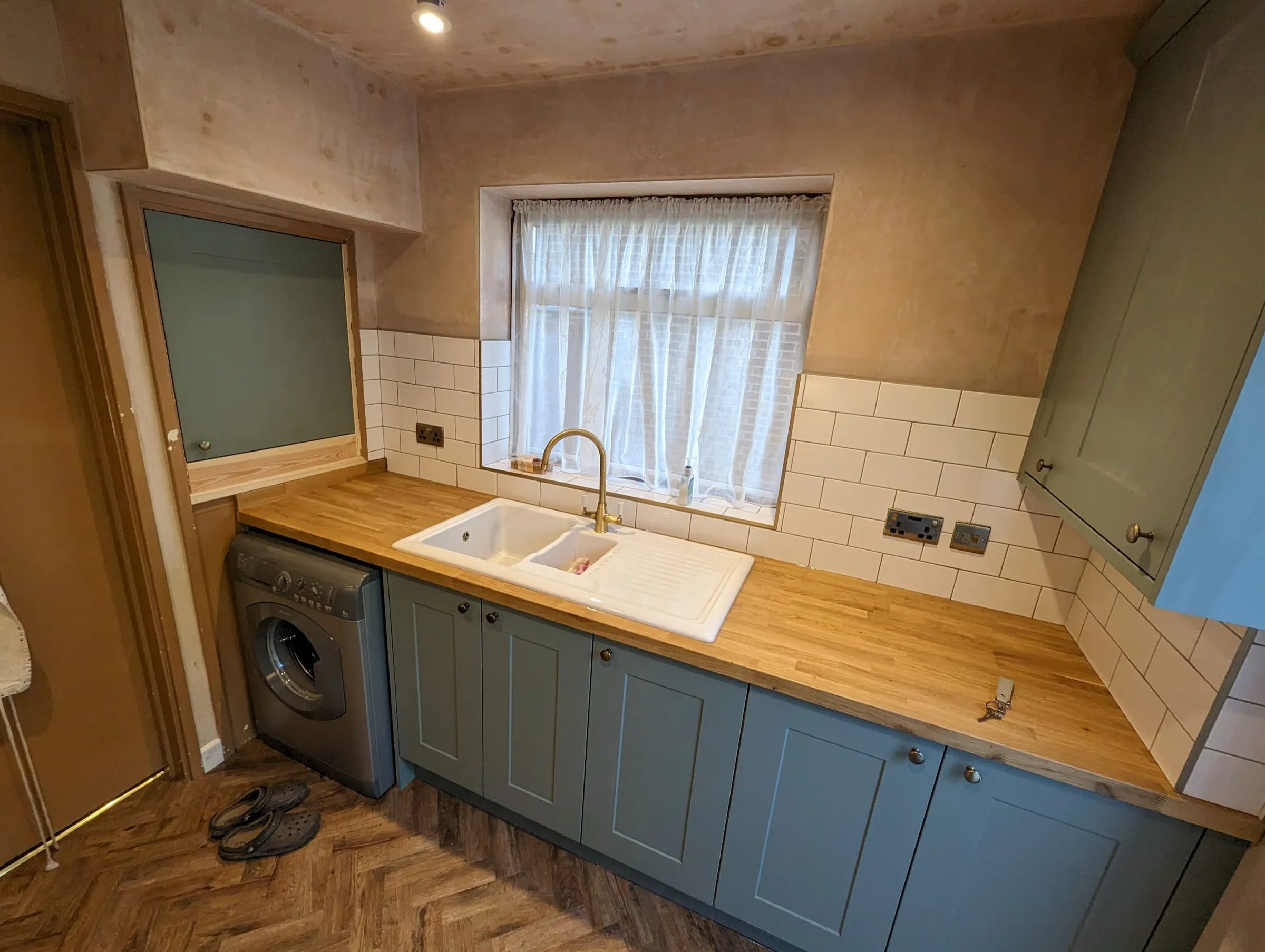 Oak worktop turning the corner of the green galley with butler-style sink