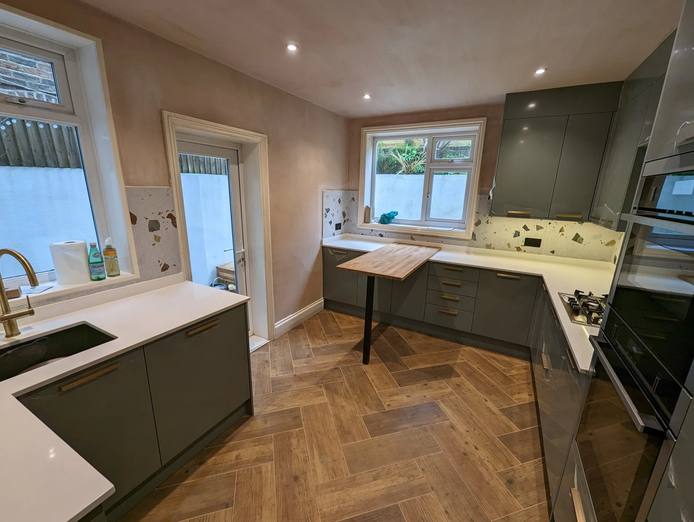 Wide view of the terrazzo kitchen with oak breakfast table and herringbone floor