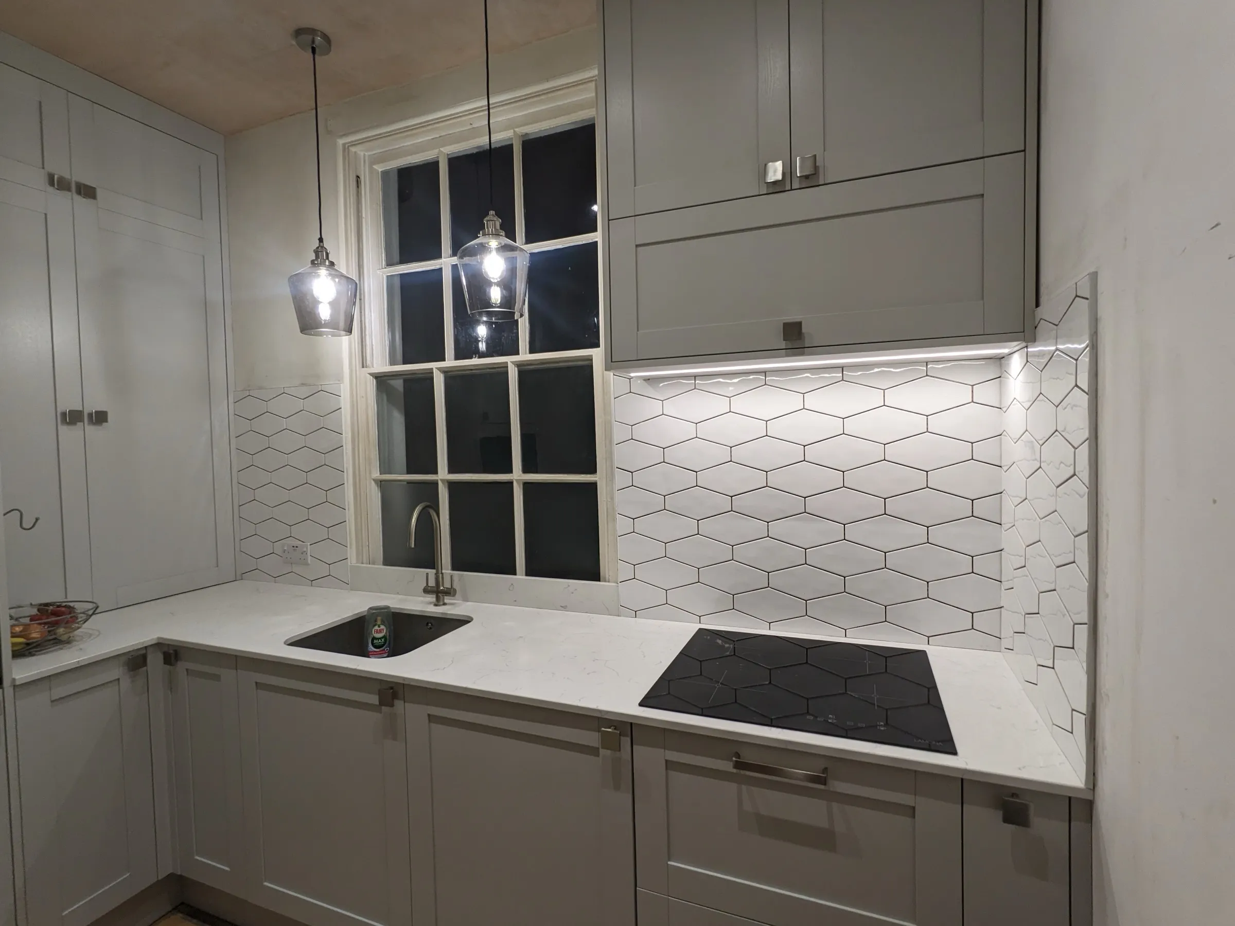 Pale grey Shaker kitchen with elongated hexagon tiles, quartz worktop and glass pendants