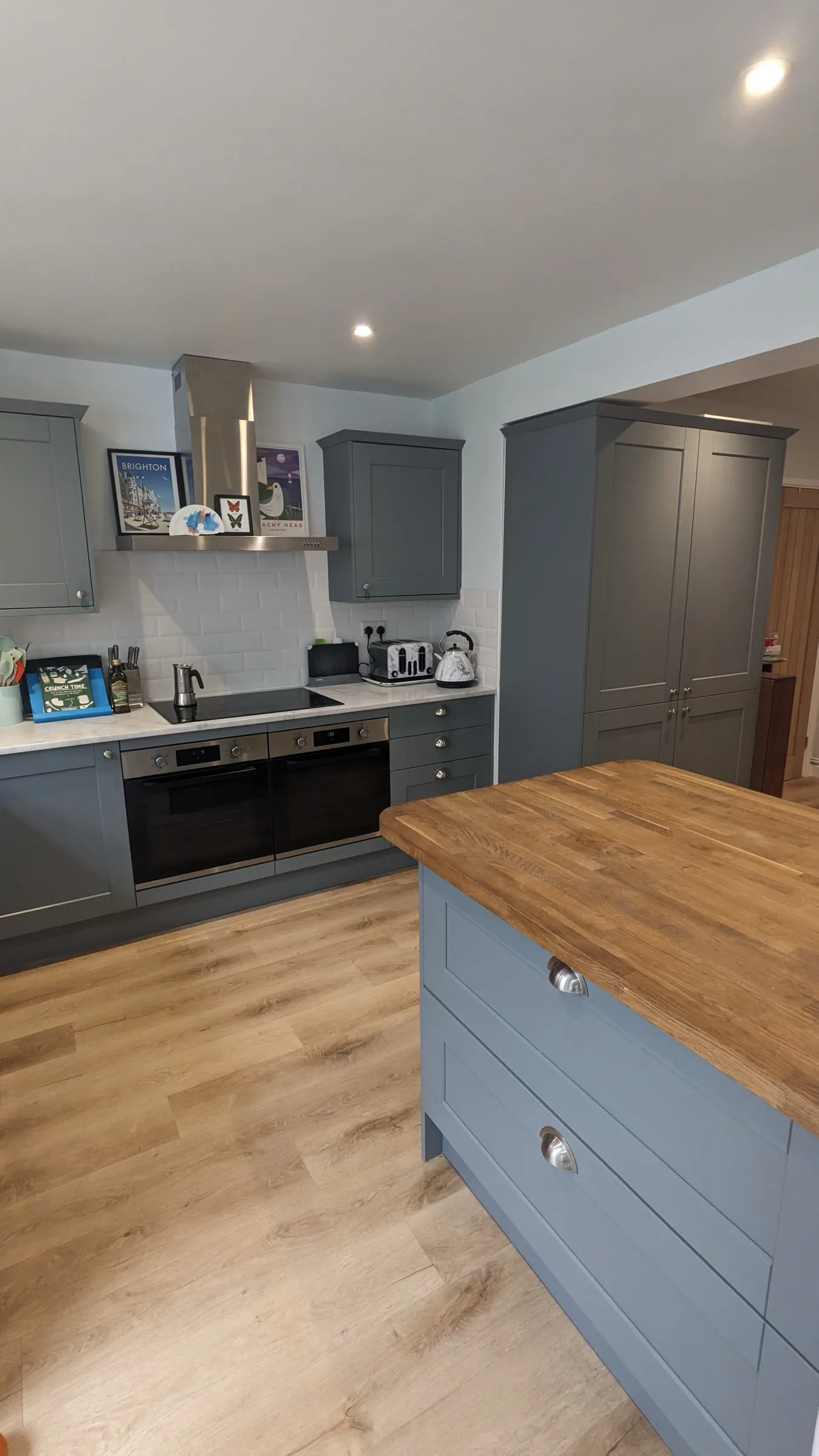 Blue-grey Shaker kitchen with oak-topped island, larder cupboards and side-by-side ovens