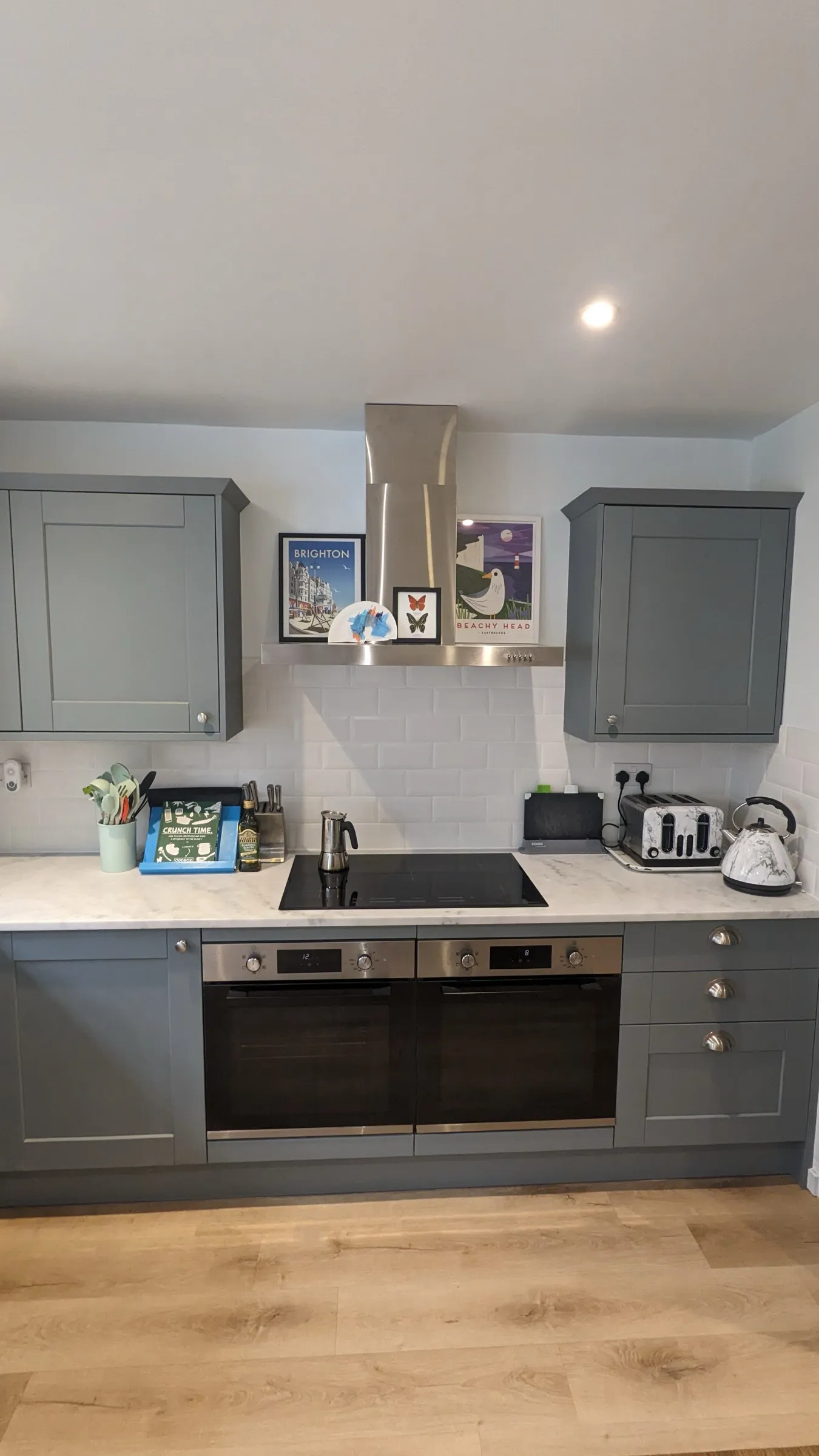 Symmetrical hob wall with stainless chimney hood and seaside prints