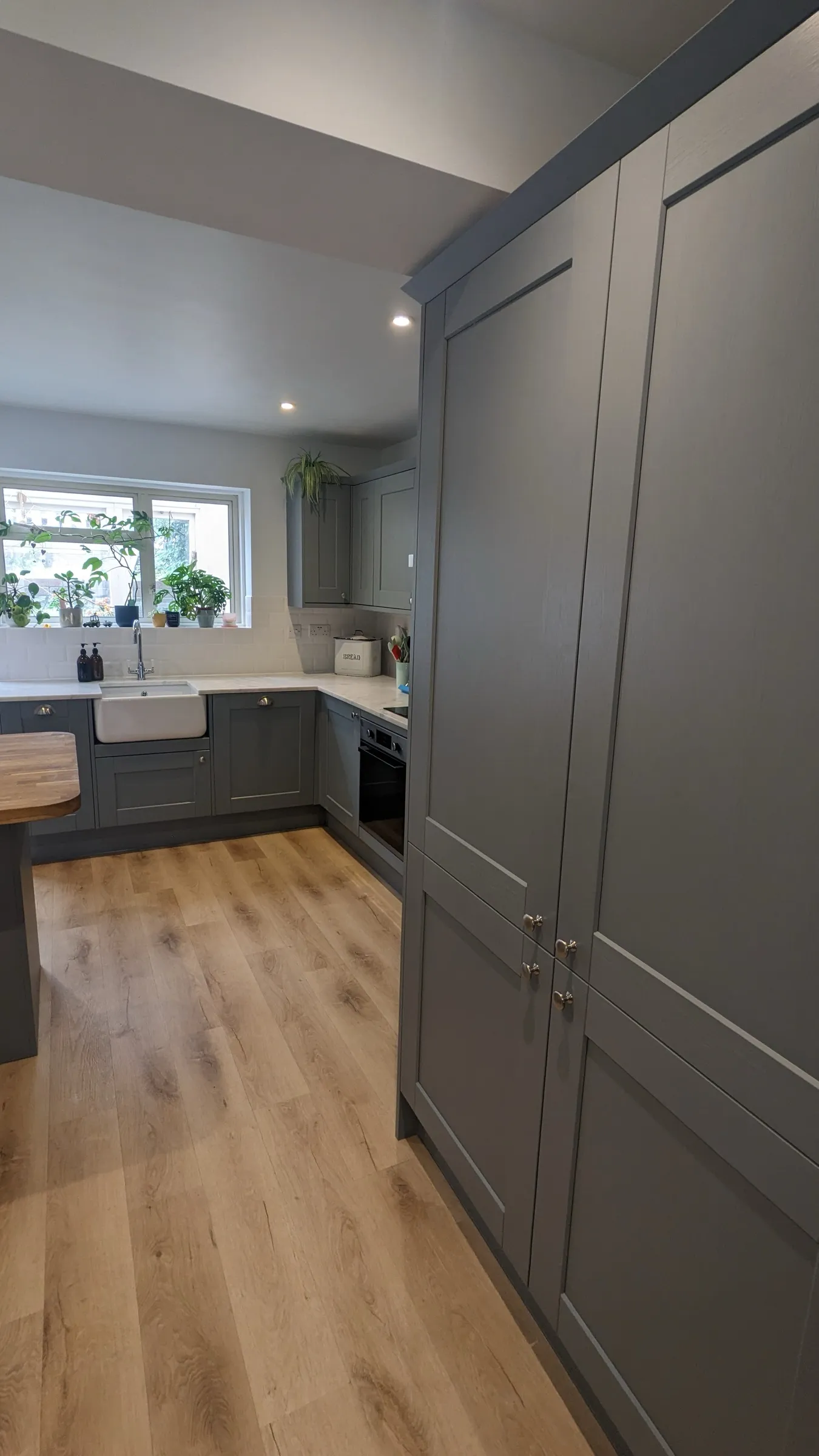 Tall blue-grey larder cupboards beside the sink run