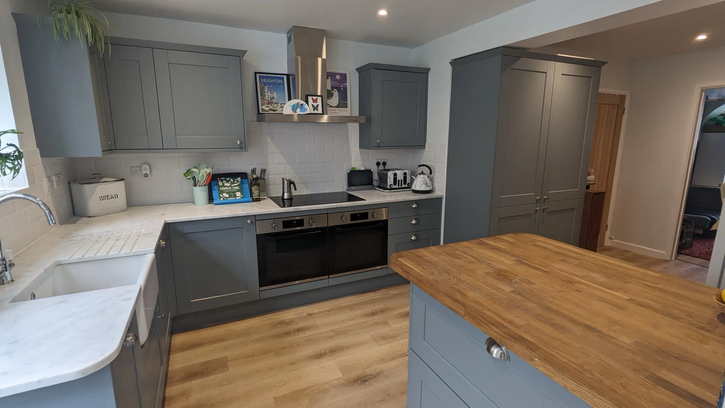 Wide view of the finished blue-grey Shaker kitchen with island and larder units