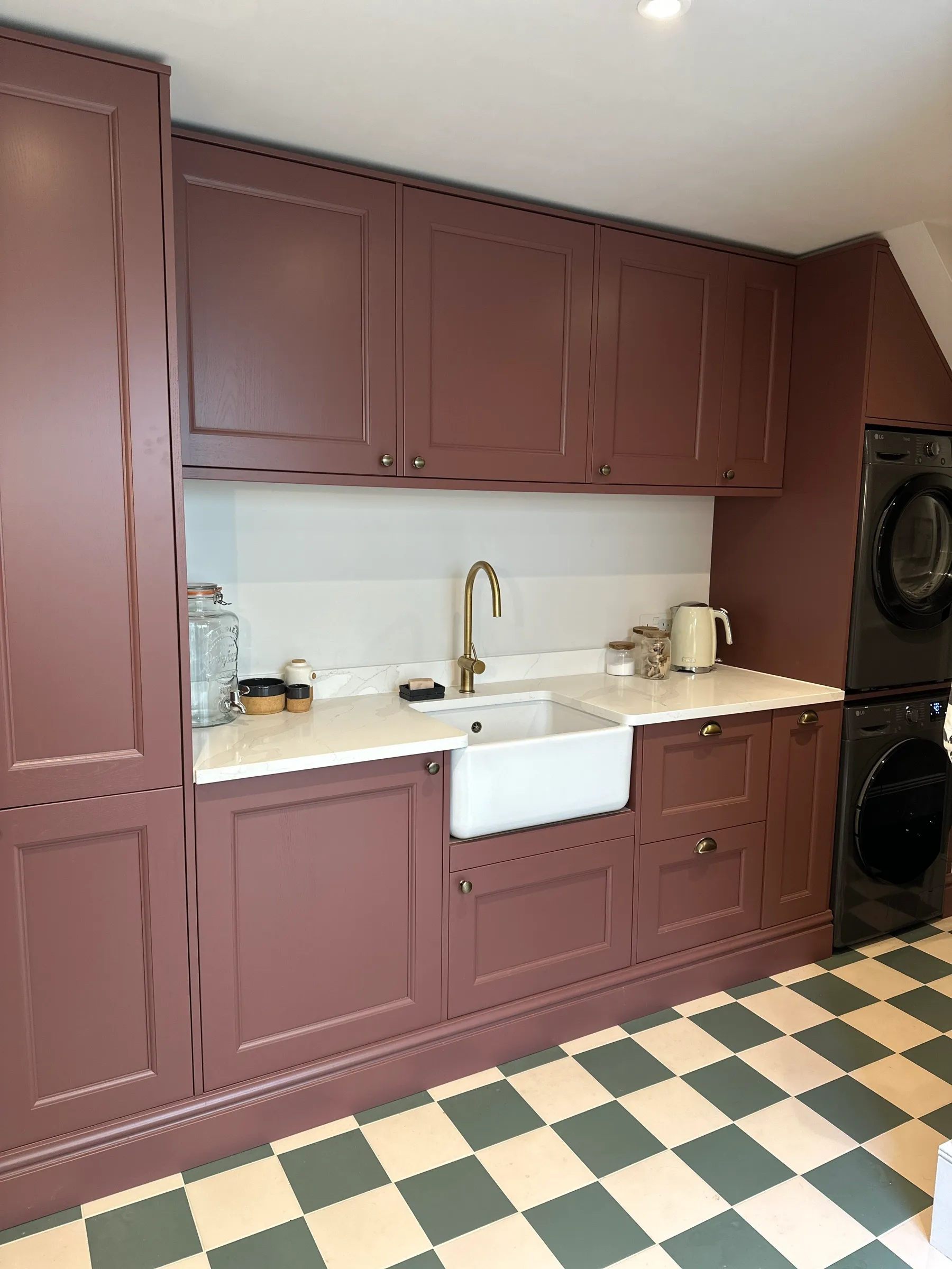 Deep maroon Shaker utility room with white quartz worktop, Belfast sink, brass tap and green and cream chequerboard floor