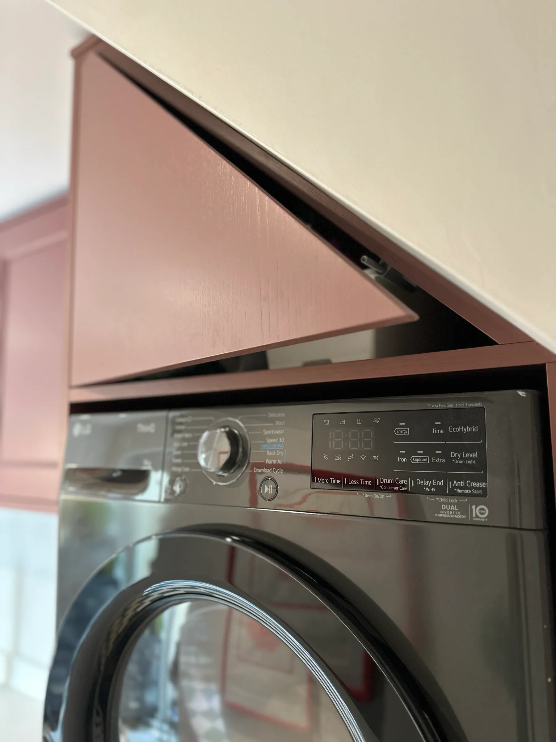 Bespoke angled cupboard door following the sloping ceiling above the integrated tumble dryer
