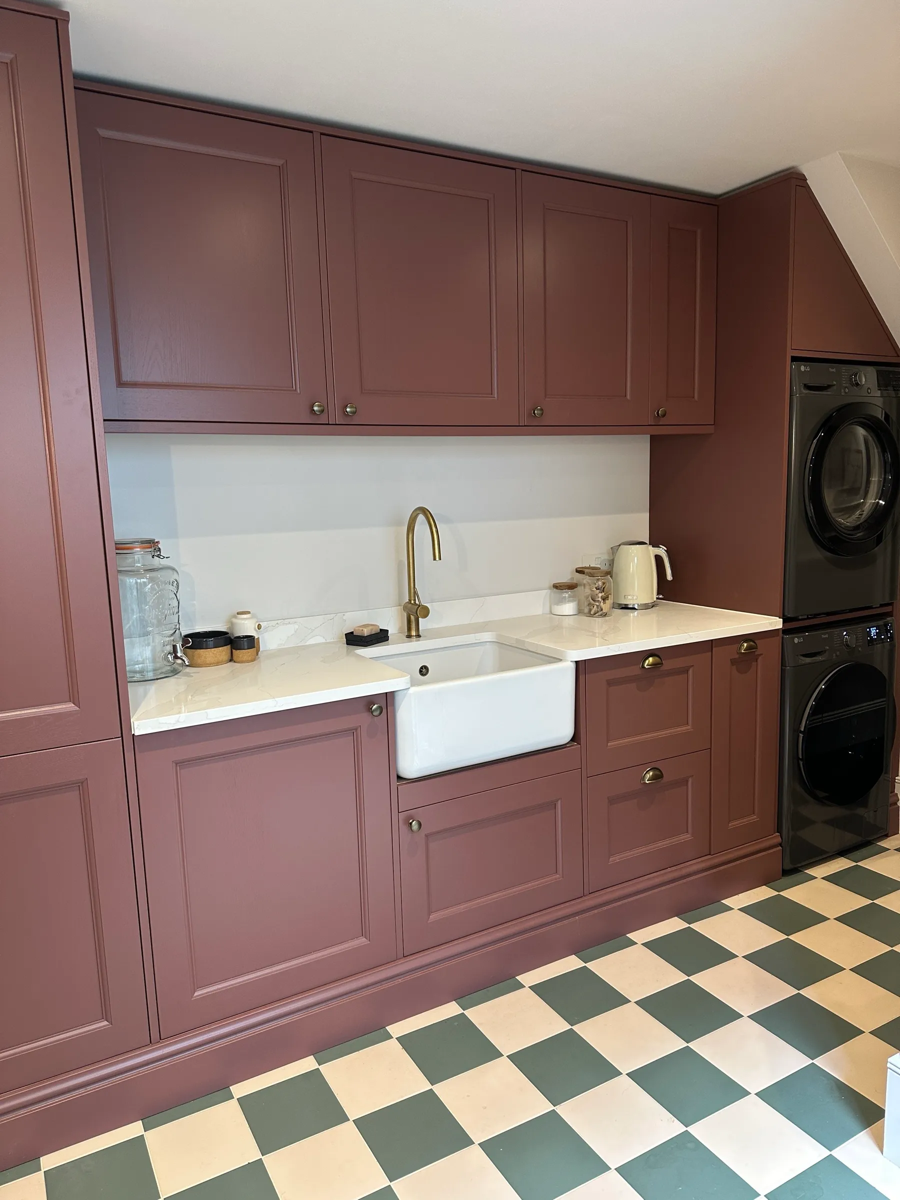 Maroon Shaker utility cabinetry with stacked washer and dryer built in beneath the sloping ceiling