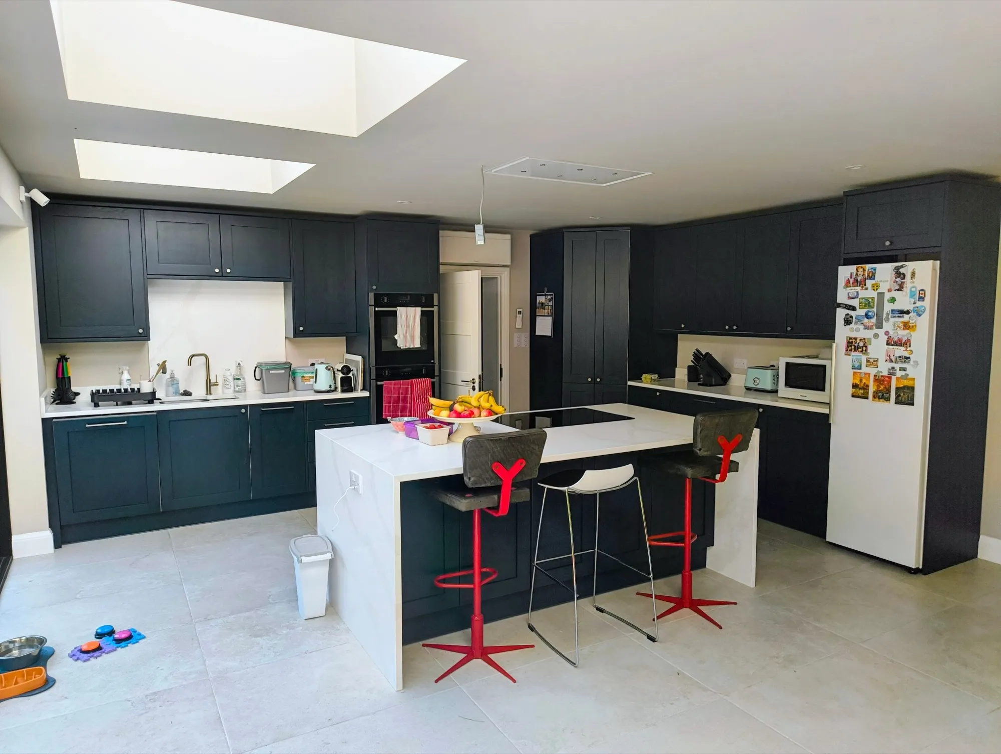 Open-plan navy Shaker kitchen with white quartz island and skylights, fitted during a full renovation
