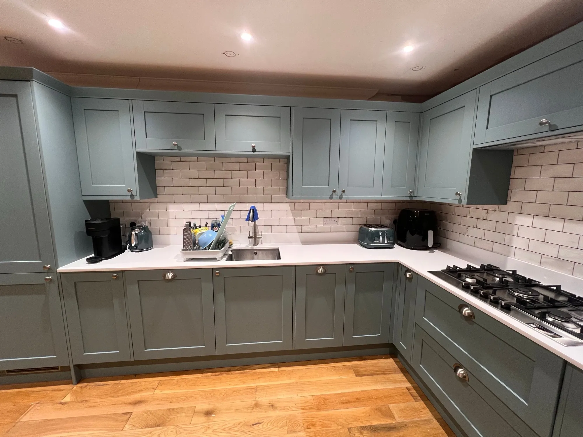 Duck egg blue Shaker kitchen with white quartz worktops, metro tiles and gas hob